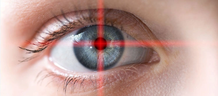 Close-up of human eye with blue-gray iris and red laser crosshair for laser eye surgery or biometric scanning